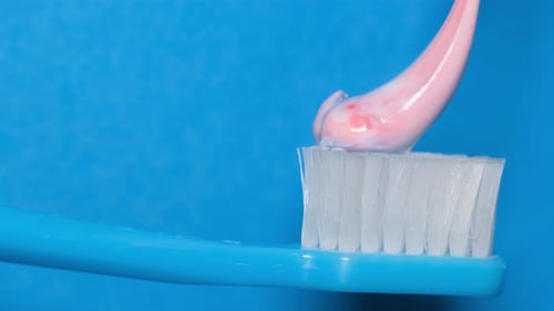 Pink Toothpaste Being Applied To Toothbrush Close Up