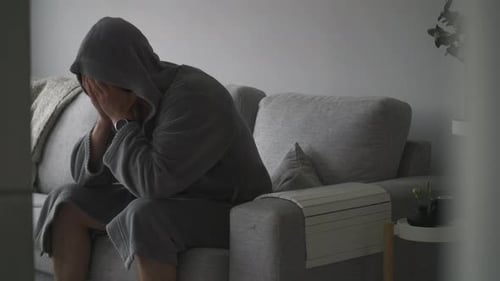 Distressed Man Covering Face While Seated on Couch