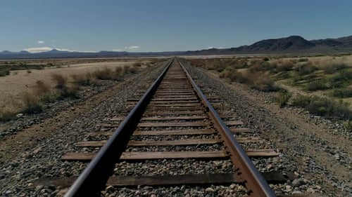 Niedrige Luftaufnahme von oben, langsam vorwärts auf geraden Eisenbahnschienen in der Wüste