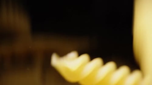 Fusilli pasta falls from top to bottom of the glass container and covers the entire space.