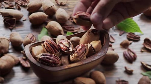 The hand takes one of the pecan nut.