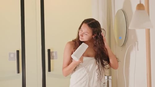 Woman Drying Long Curly Hair in Bathroom with Dryer