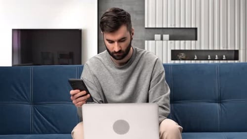 Business Man Working Smartphone Laptop at Home Office Sitting Couch Modern Apartment