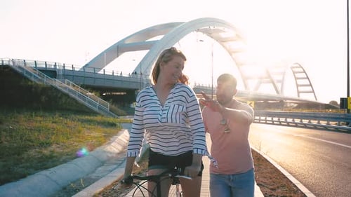 Cheerful young couple having fun riding on bicycle on summer day.