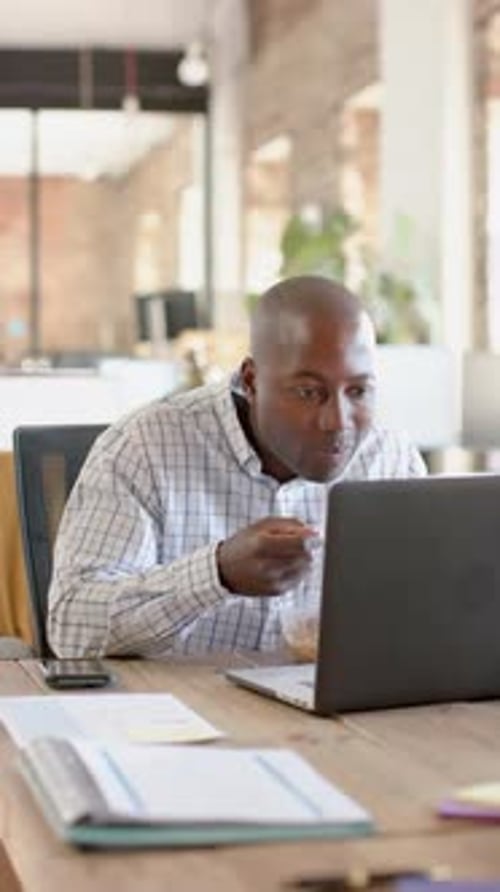 Man Works at Computer and Eats Lunch