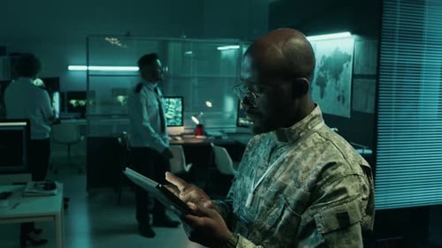 Black Male Army Commander Using Tablet with Satellite Maps in Operations Center