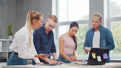 Team of Young Startupers is Working at the Table in the Office Discussing the Strategy and