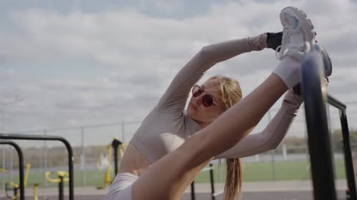 Woman Stretches on Exercise Bars in Urban Park