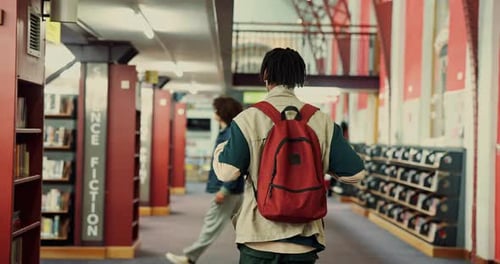 Homem, faculdade e estudante caminhando pela biblioteca em busca de material de estudo, pesquisa de livros didáticos e conhecimento