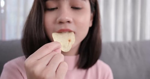 Close up asian woman takeaway eating chips junk food, trans fats