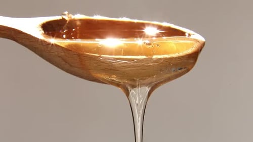 Natural Honey Slowly Flows Out of the Spoon in a Thin Stream