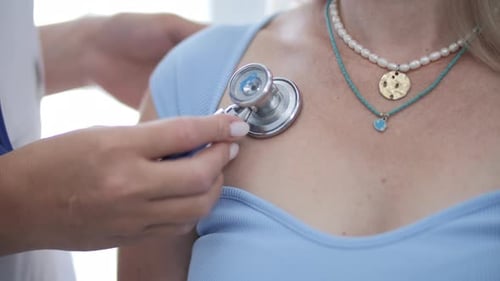 Doctor listens to woman's heartbeat with stethoscope