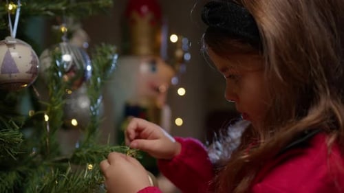 Child Decorating Christmas Tree with Festive Ornaments