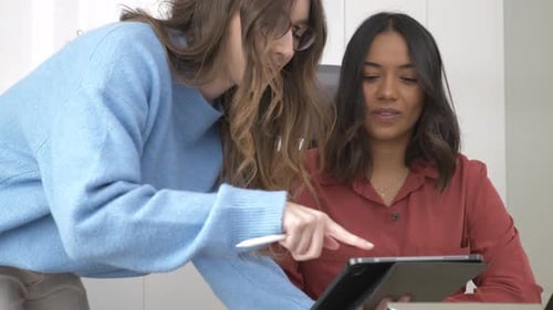 Businesswomen Collaborating on Tablet with Stylus in Office