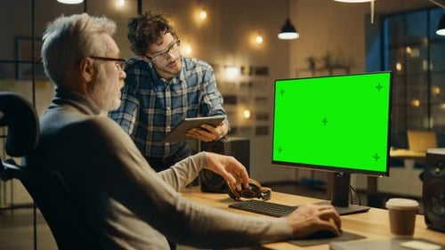 Am Abend arbeitet ein kreativer Mann mittleren Alters an einem Desktop-Computer, grüner Mock-up, Has Conve