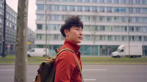 Mochileiro asiático atraente andando por uma bela estrada na cidade.