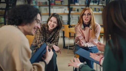 Groupe de jeunes adultes participant à une discussion dans une bibliothèque pendant l'après-midi avec
