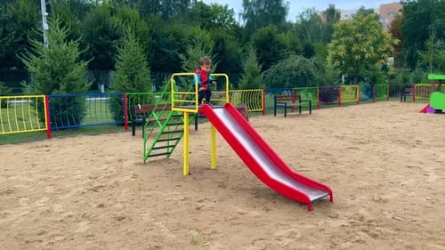 Child Slides Down Colorful Playground Slide