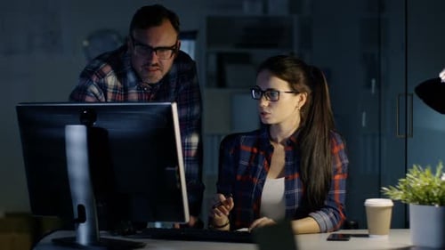 Late Night at the Office. Male and Female Colleagues Discuss Work Done on Her Personal Computer. In