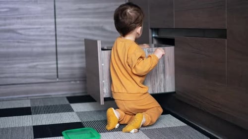 Child Plays with Food Containers in Kitchen Drawer