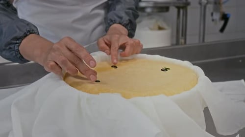 Female Factory Worker Placing Batch Numbers on top of Cheese Head