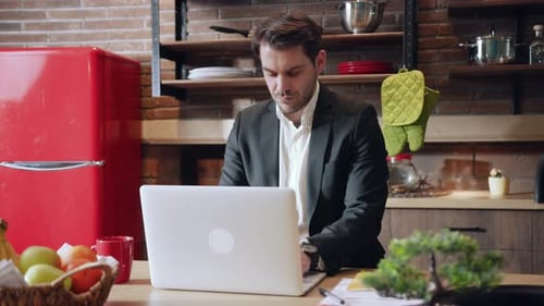 A Professional Person is Working Efficiently in a Modern Kitchen While Using a Laptop