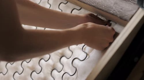 Closeup of a Young Girl is Trying to Repair the Spring of the Sofa