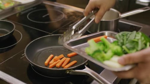 Restaurant Chef Sauteing Broccoli and Carrot in Frying Pan on Stove