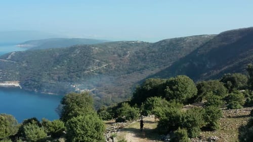 Man With Pet Dog Running on Mountain Trail With A View Adriatic Sea In Cres Island, Croatia. - aeria