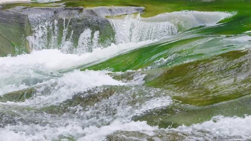Stormy streams of water and waterfalls of a mountain river. Slow motion.