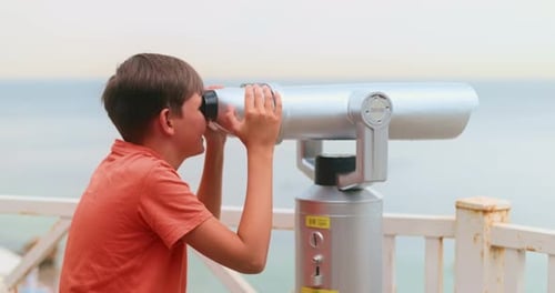 Boy Observing Ocean View Through CoinOperated Binoculars