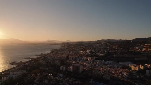 City with houses and apartments next to the sea, cinematic scene with golden sky at sunset. Aerial