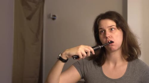 Mujer joven cepillándose los dientes en el baño 4K