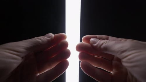 Hands Reaching Towards Bright Light on Dark Background