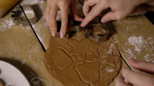 Hands Cutting Christmas Cookie Shapes out of Dough