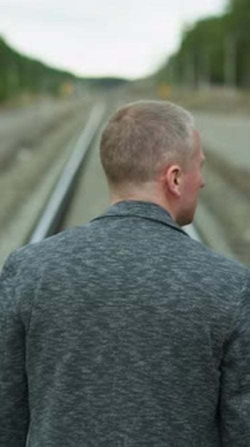 Man Walking Along Railroad Tracks in Nature