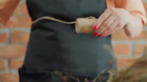 Florist in Black Apron Holding Spool of Twine with Both Hands
