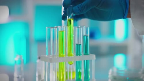 Glass. A male scientist in a white coat carefully analyzes liquids in a modern research center