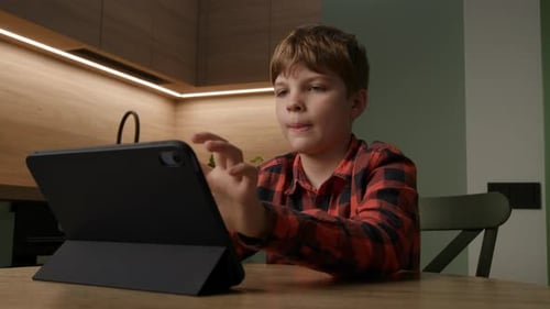 Schoolboy Engages with Tablet Computer While Home Learning