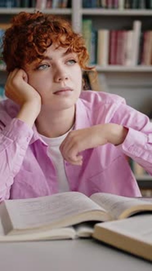 Frustrated Student Studying at Desk in Library