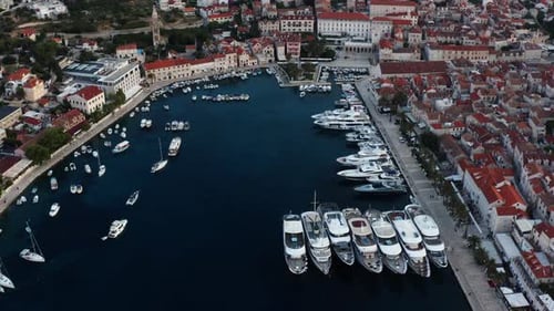 Luxury Yachts And Boats Dock At Marina With Waterfront Buildings At Sunrise In Hvar, Croatia. - aeri