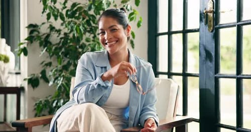Smiling Woman in Chair at Home Removes Glasses