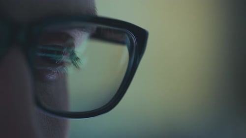 Adult with Glasses Looking at Computer Screen at Night
