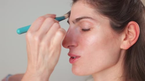 Makeup Artist Applying Blusher on Woman's Face in Beauty Studio