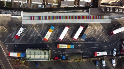 A steady top down shot of busses leaving the bus depot.