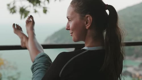 Mujer joven relajándose en el balcón disfrutando de una hermosa vista tropical
