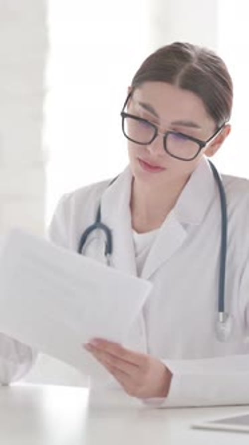 Femme médecin lisant des documents au bureau, Vidéo verticale