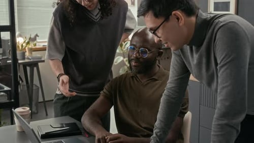 Zwei Webentwickler diskutieren Software mit einem Programmierer, der am Schreibtisch sitzt