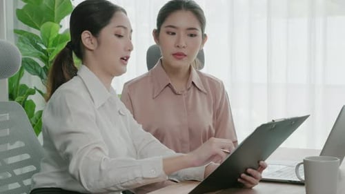 Two Young Enthusiastic Businesswoman Working Together in the Office Workspace