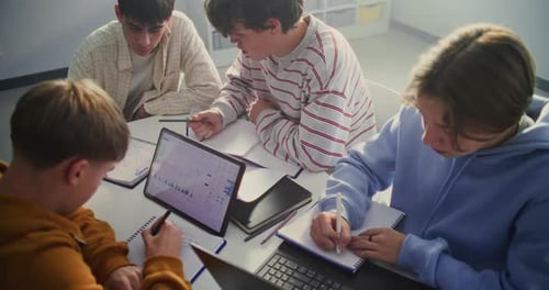 Small Group of Teenagers Engaged in Digital Learning Task Centered Around Tablet